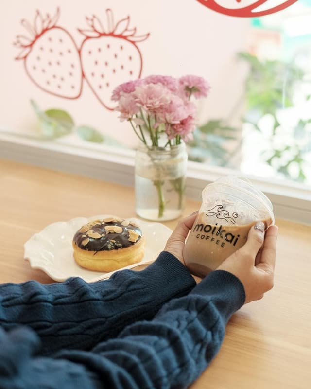 Holding a cold coffee latte next to a chocolate donut