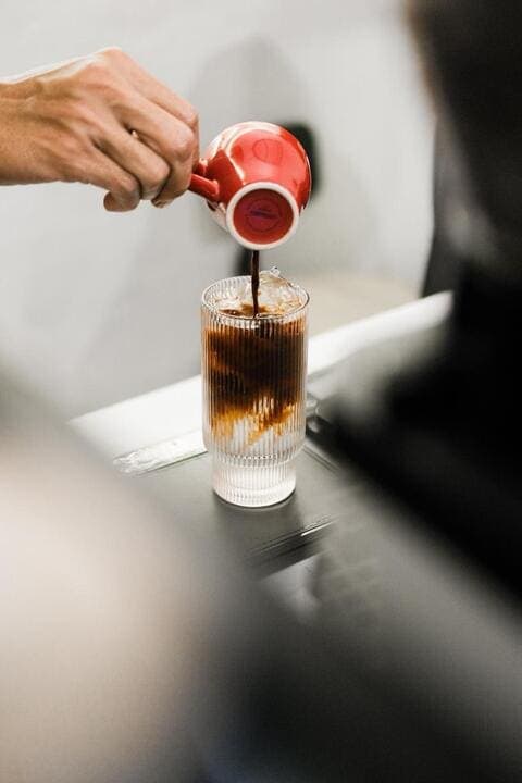 Pouring fresh espresso into an iced latte